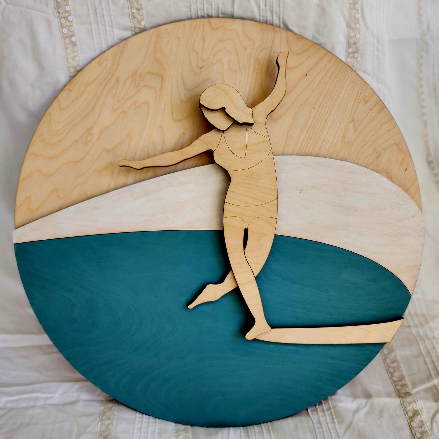 An artwork made from plywood featuring a surfer poised elegantly on the nose of her surfboard.
